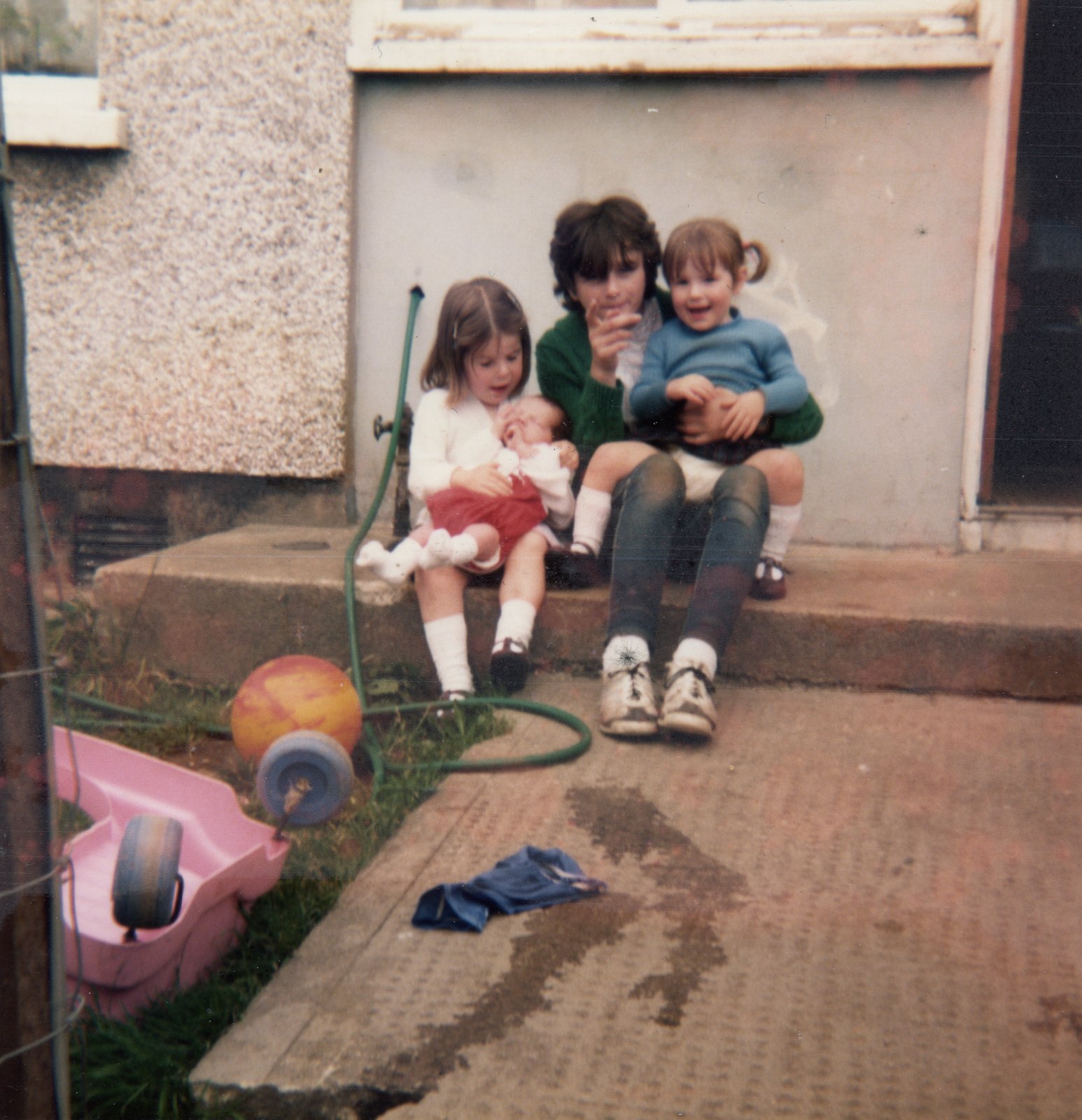 Portrait of siblings Lisa, Tracy and Gary Crowne with Siobhán McCrory, on the back steps of the family home at O’Kane Park, outside of Omagh, County Tyrone, in 1985.